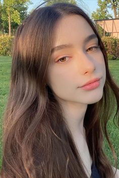 Young woman with long brown hair outdoors in soft golden hour light