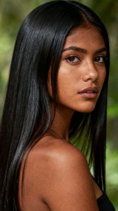 Woman with long black hair looking over her shoulder outdoors