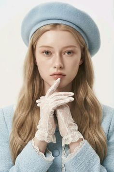 Woman with blonde hair wearing a blue beret and lace gloves