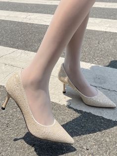 Person wearing glitter high heels and white tights on a zebra crossing
