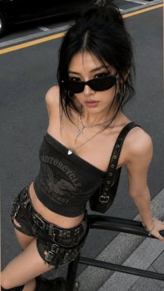 Woman with black hair and sunglasses wearing a tube top and denim shorts outdoors