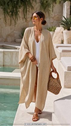 Woman in a kaftan and swimsuit walking poolside