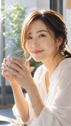 Woman with brown hair holding a cup, smiling in soft lighting
