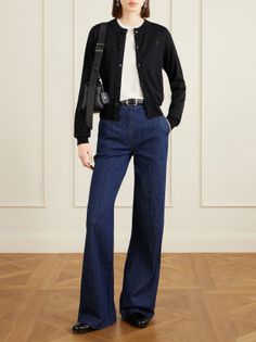 Woman in a black cardigan and wide leg jeans standing indoors