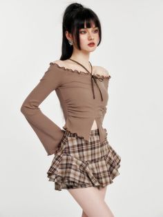 Woman with a ponytail wearing an off-shoulder top and plaid skirt