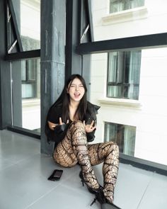 Woman in fishnet stockings and a leather jacket making a rock and roll gesture