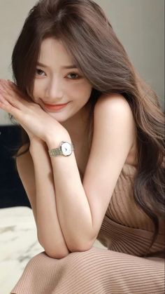 Woman with long brown hair wearing a sleeveless top and a watch, smiling at the camera