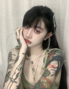 Woman with long dark hair, full sleeve tattoos, and a lip piercing