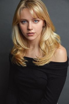 Blonde woman with blue eyes wearing an off-shoulder black top