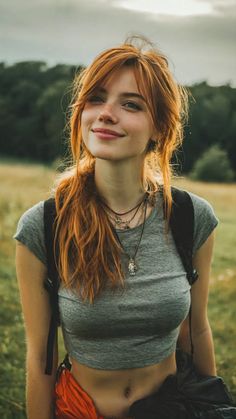 Woman with red hair and freckles wearing a crop top and backpack outdoors