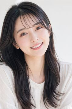 Woman with long black hair smiling in a white shirt