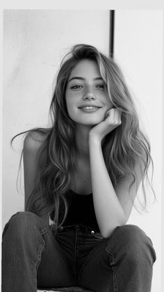 Smiling woman with long hair and freckles, resting her chin on her hand