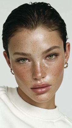 Woman with freckles, short hair, and green eyes wearing gold hoop earrings