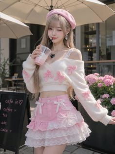 Woman in a pink beret and a white sweater with pink bows, holding a drink