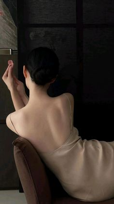 Woman with bare back and updo in a slip dress, holding a small flower