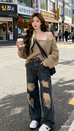 Woman with long wavy hair and ripped jeans holding a coffee cup on a street