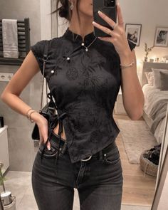 Woman in a black high-neck top and jeans taking a mirror selfie indoors