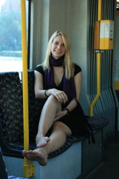 Blonde woman in a black dress and purple scarf sitting indoors