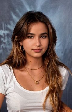 Young woman with long brown hair and gold jewelry wearing a white t-shirt