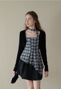 Woman in a plaid dress and black cardigan with a matching choker indoors