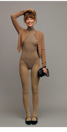 Woman in a brown bodysuit and ribbed tights with a cardigan and black handbag