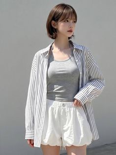 Woman with short hair wearing a striped shirt and white shorts outdoors