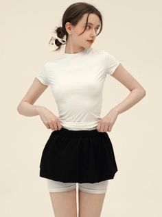 Woman in a white t-shirt and black skirt with white shorts underneath