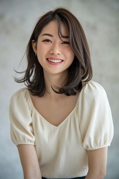 Smiling woman with short brown hair wearing a cream v-neck top