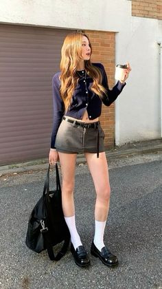 Woman in a crop top and mini skirt holding a coffee cup on a street