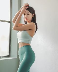 Woman in a sports bra and yoga pants posing indoors