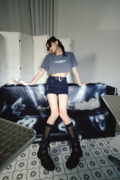 Woman in a crop top and mini skirt with braids and sunglasses indoors