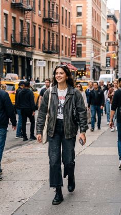 Woman in a leather jacket and distressed jeans walking on a city street