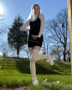 Woman with long hair in a black dress and white turtleneck outdoors