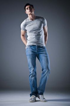 Man in a grey t-shirt and blue jeans posing in a studio
