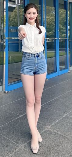 Woman in denim shorts and a white shirt standing outdoors