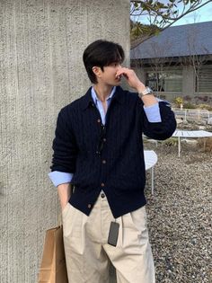 Man in a navy cardigan and light blue shirt outdoors