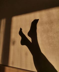 Shadow of legs and feet cast on a warm-toned wall