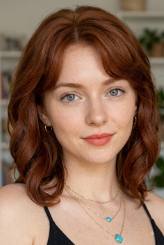 Woman with red wavy hair and blue eyes wearing layered turquoise necklaces