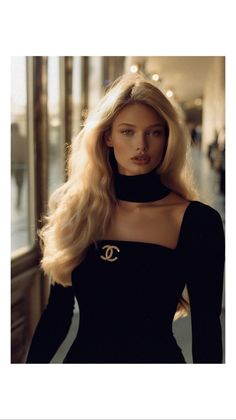Woman with long blonde hair wearing a black dress and choker indoors