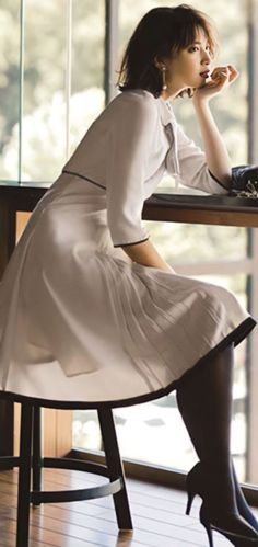 Woman in a white dress and black stockings sitting indoors