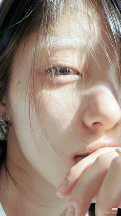 Close up of a person's face with hair covering part of it, fingers on lips