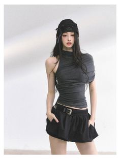 Woman with long black hair wearing a black hat and gray top with black shorts