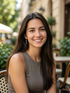 Smiling woman with long dark hair wearing a sleeveless top outdoors