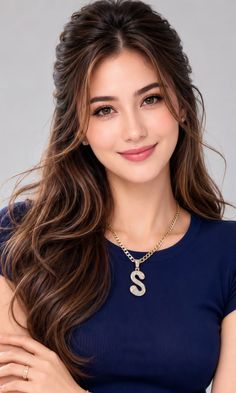 Woman with long brown hair wearing a dark blue top and a gold initial S necklace
