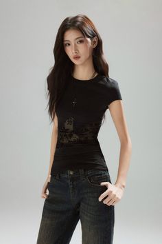 Woman with long dark hair wearing a black t-shirt and jeans in a studio