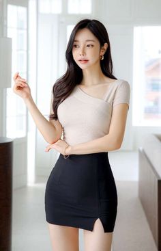 Woman with long black hair wearing a beige top and black mini skirt indoors