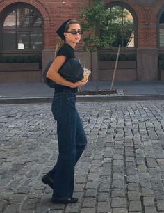 Woman with blonde hair and sunglasses walking on a cobblestone street