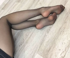 Legs in black pantyhose on a light wooden floor