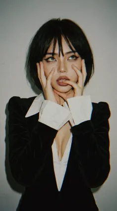 Woman with short black hair and a black jacket with a deep V-neckline