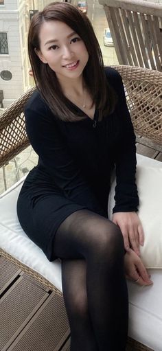 Woman with long hair wearing a black dress and tights, sitting outdoors